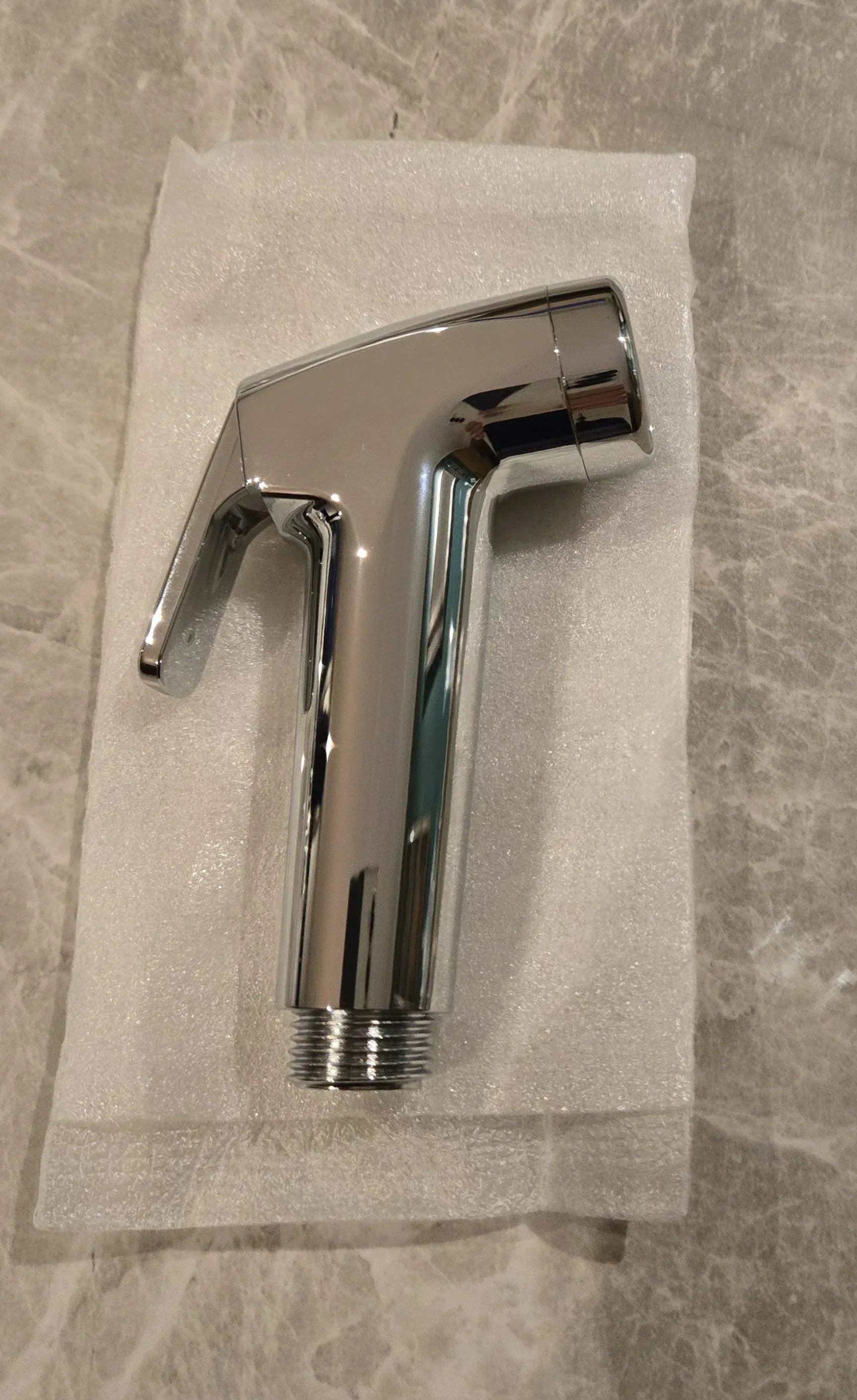 Angled view of handheld bidet sprayer showing nozzle and trigger design