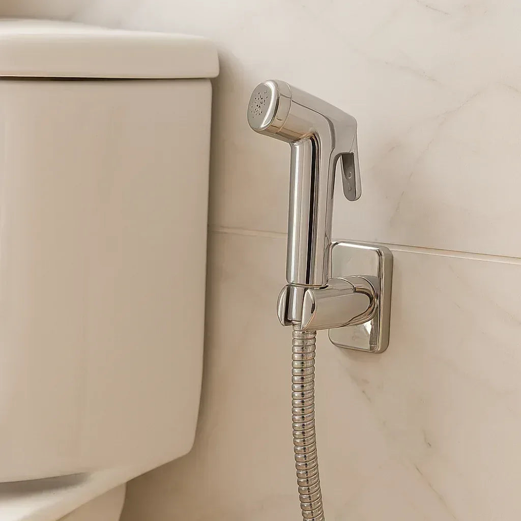 Chrome bidet sprayer installed on side of toilet with wall bracket
