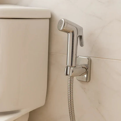 Chrome bidet sprayer installed on side of toilet with wall bracket